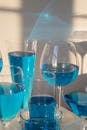 Closeup composition of crystal clear glasses filled with blue shaded drink in sunlight