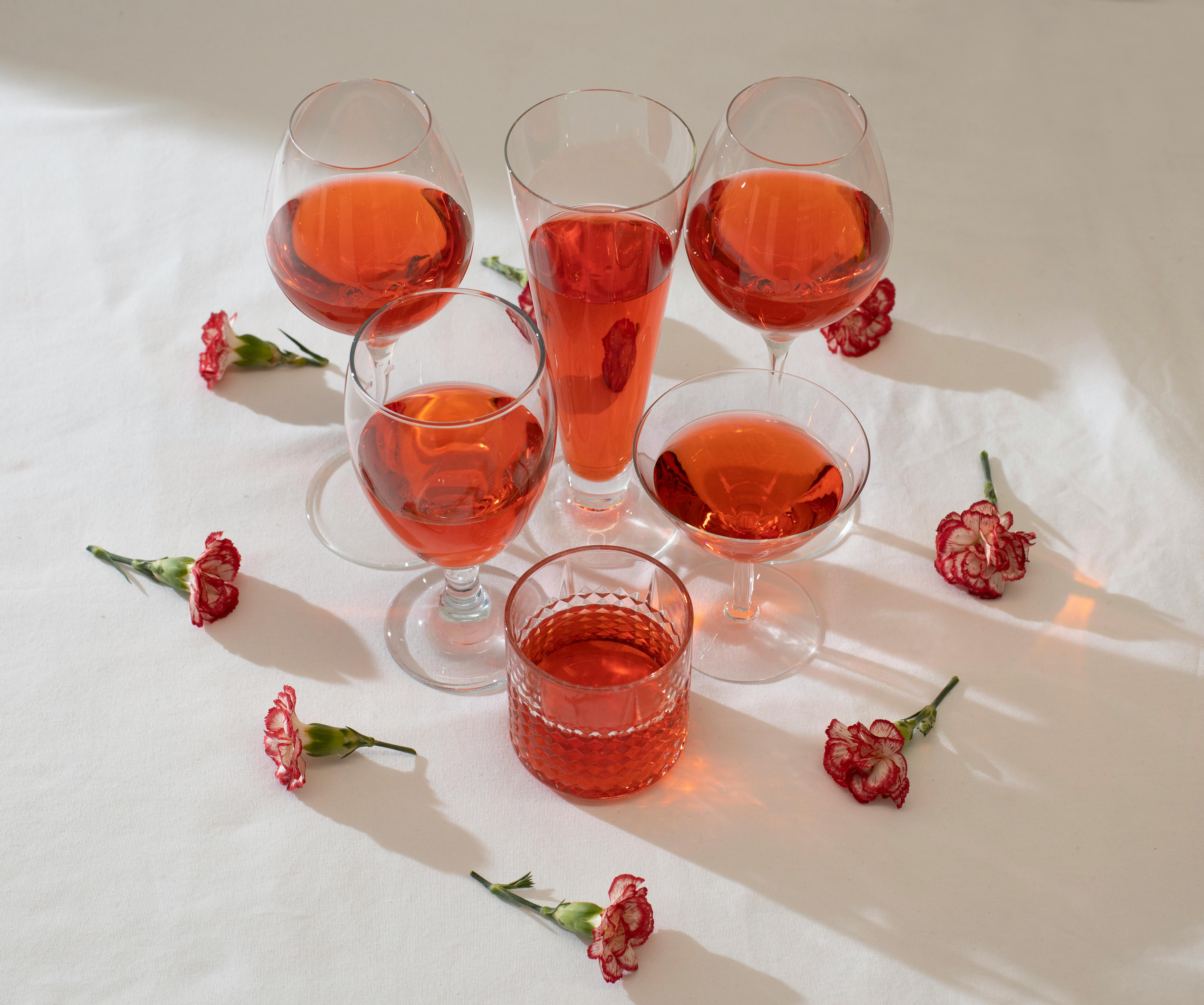 红色饮料点缀着康乃馨，盛放在各种玻璃器皿中，显得时尚而精致