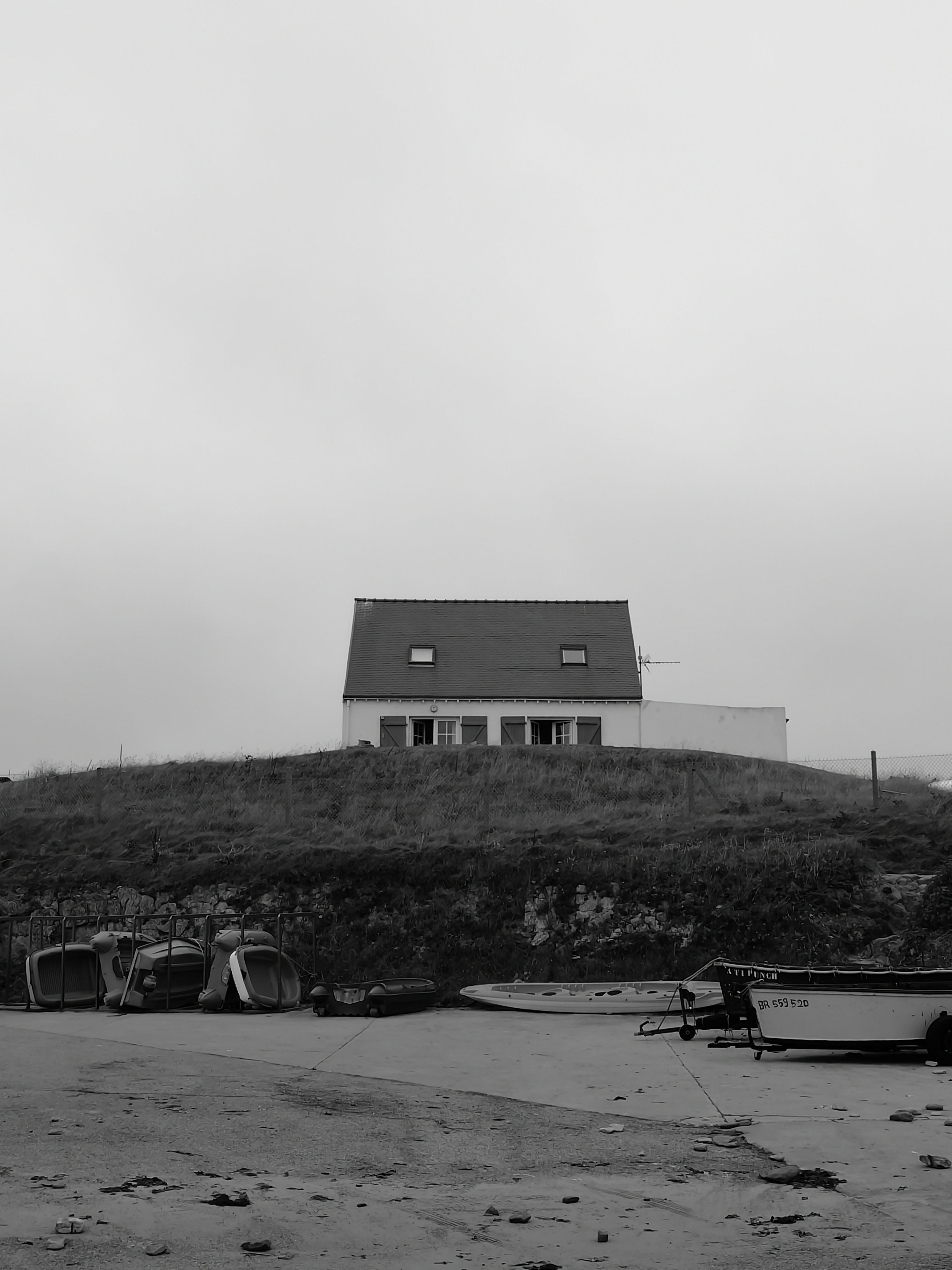 A solitary house on a cliff in Clohars-Carnoët, Bretagne, captured in grayscale.