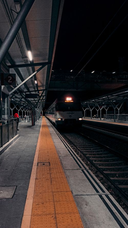 Free A train arriving at a modern railway station at night, with empty platforms and lit tracks. Stock Photo
