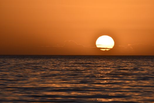 Mesmerizing sunset over calm ocean waters with a golden sky reflecting in the sea.