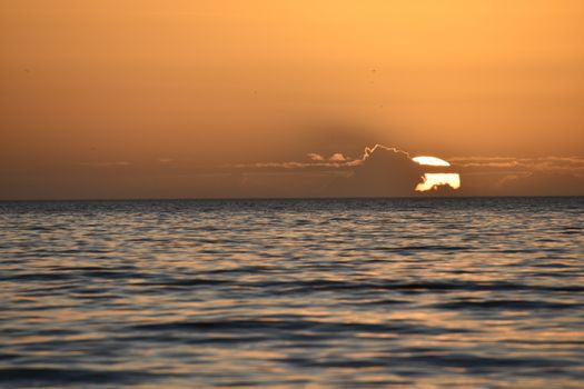 Beautiful sunset over ocean with orange and golden hues, creating a serene and calming atmosphere.