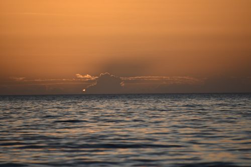 Free A soothing ocean sunset with golden hour skies and distant clouds over calm waters. Stock Photo