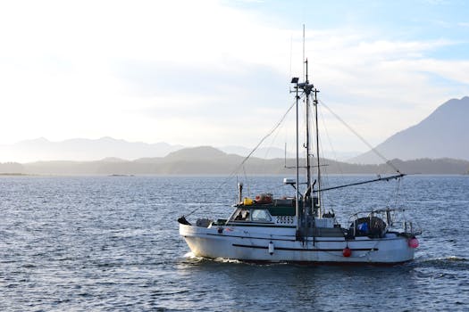 A lone commercial fishing boat navigating calm waters with mountain backdrop.