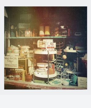Charming vintage shop window with retro items, including dishware and decor, in nostalgic hues.