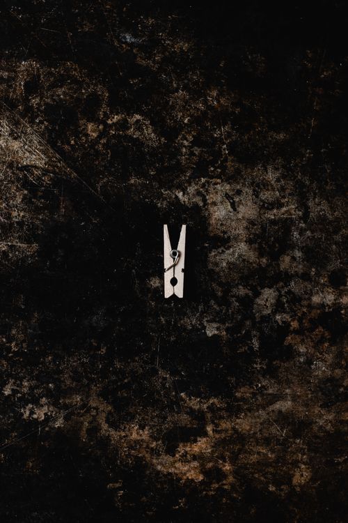 Free A single wooden clothespin placed against a textured, grungy background. Dark and moody tones. Stock Photo