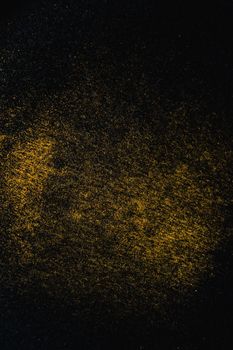 黑色表面上散布着金色粉末，形成一幅纹理丰富的抽象艺术作品