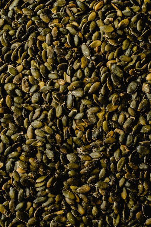 Free High-resolution close-up of a textured surface covered in organic pumpkin seeds, ideal for health and food themes. Stock Photo