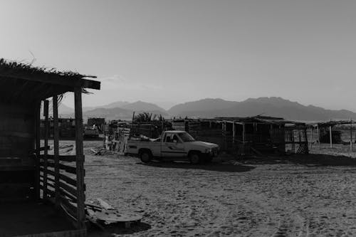 Grayscale Photo of a Pickup Car Parked on the Sand