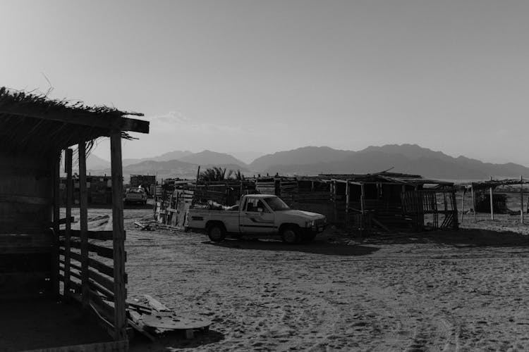 Grayscale Photo Of A Pickup Car Parked On The Sand