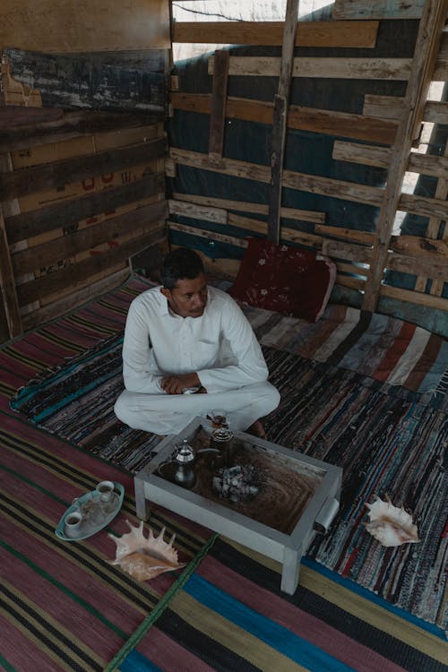 Man in White Thobe Sitting on Floor