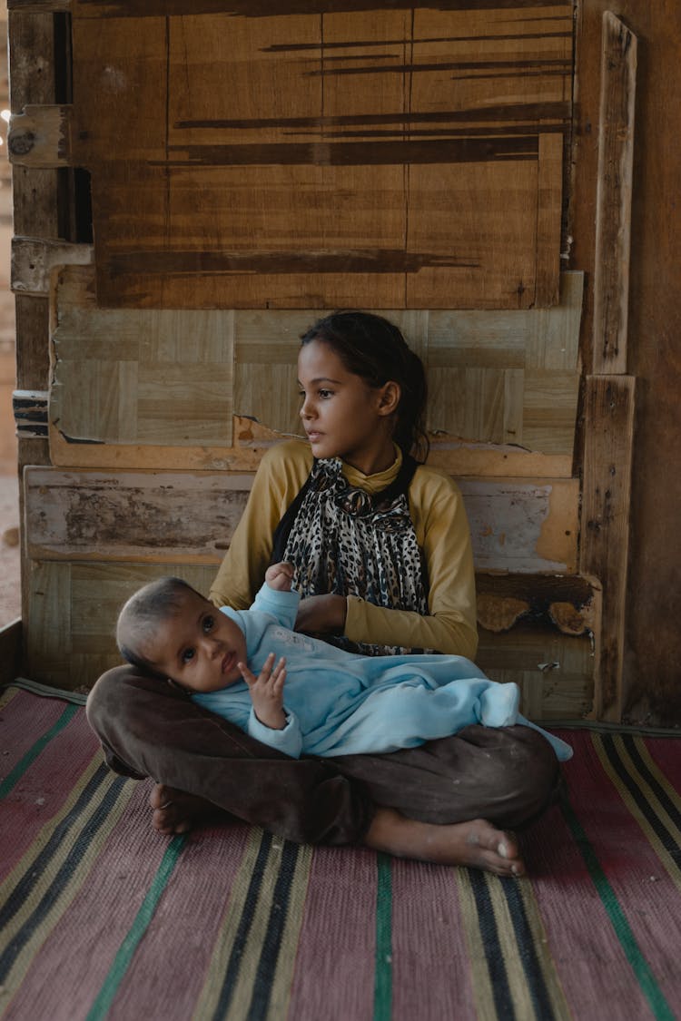 Woman In Black And Yellow Dress Sitting With Baby On Her Lap