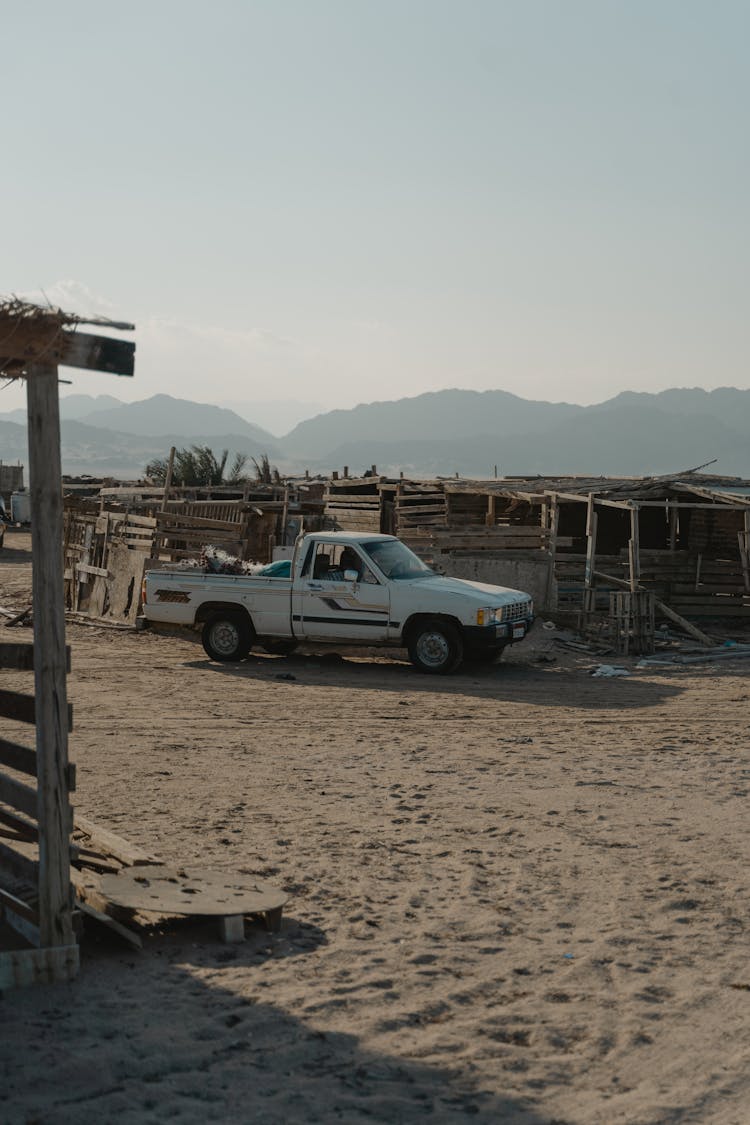 A White Pickup Car Parked On The Sand