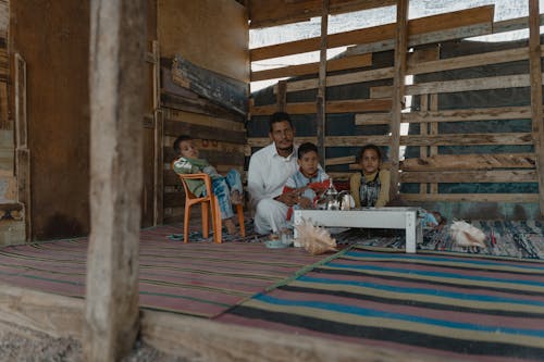 A Man Sitting in a Shack with his Children