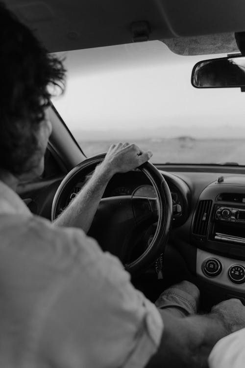 Grayscale Photo of a Person Driving a Car