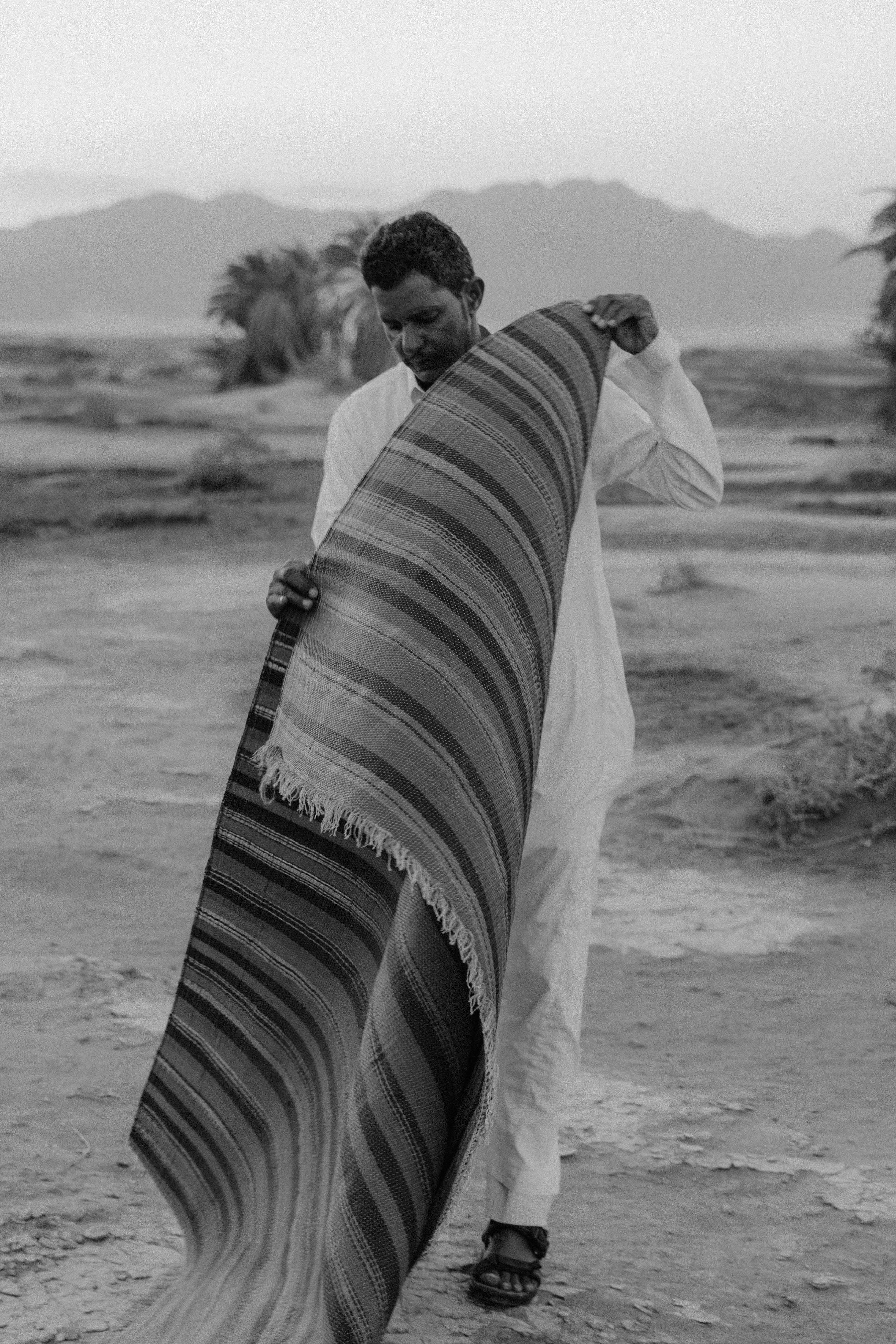 man in white dress shirt holding a carpet