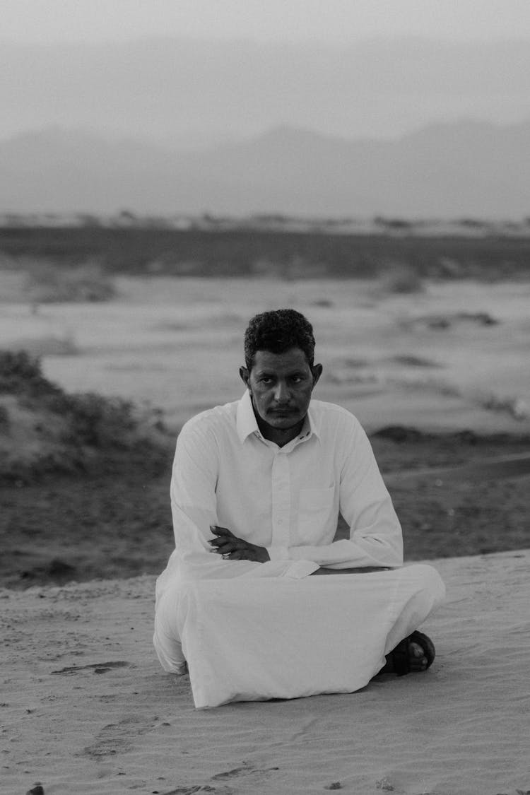 Grayscale Photo Of A Man Sitting On The Ground