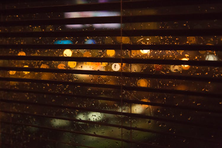 Blurred Lights Behind The Window Wet From Rain At Night 