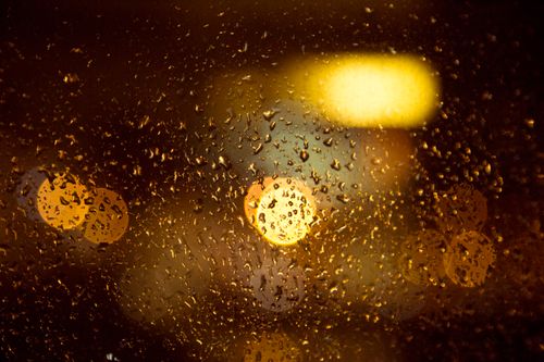Free Wet window with droplets and glowing lights of modern city in rainy evening Stock Photo