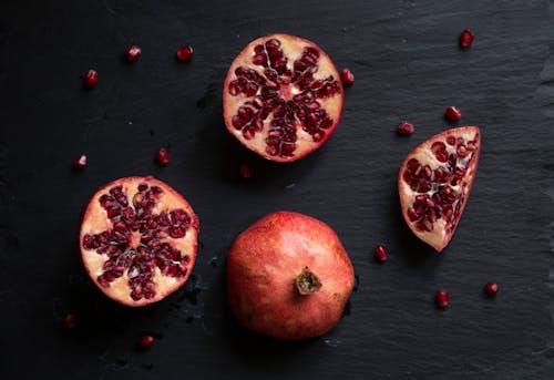 Close-Up Shot of Slices of Pomegranate on a Black Surface