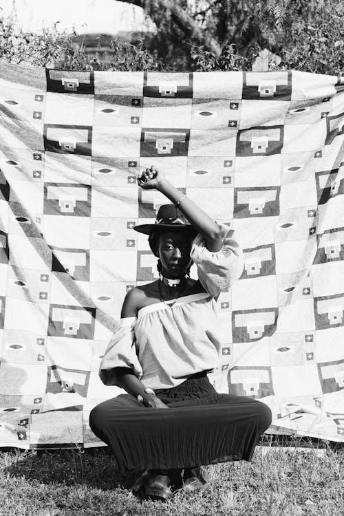 Black woman sitting against fabric in garden