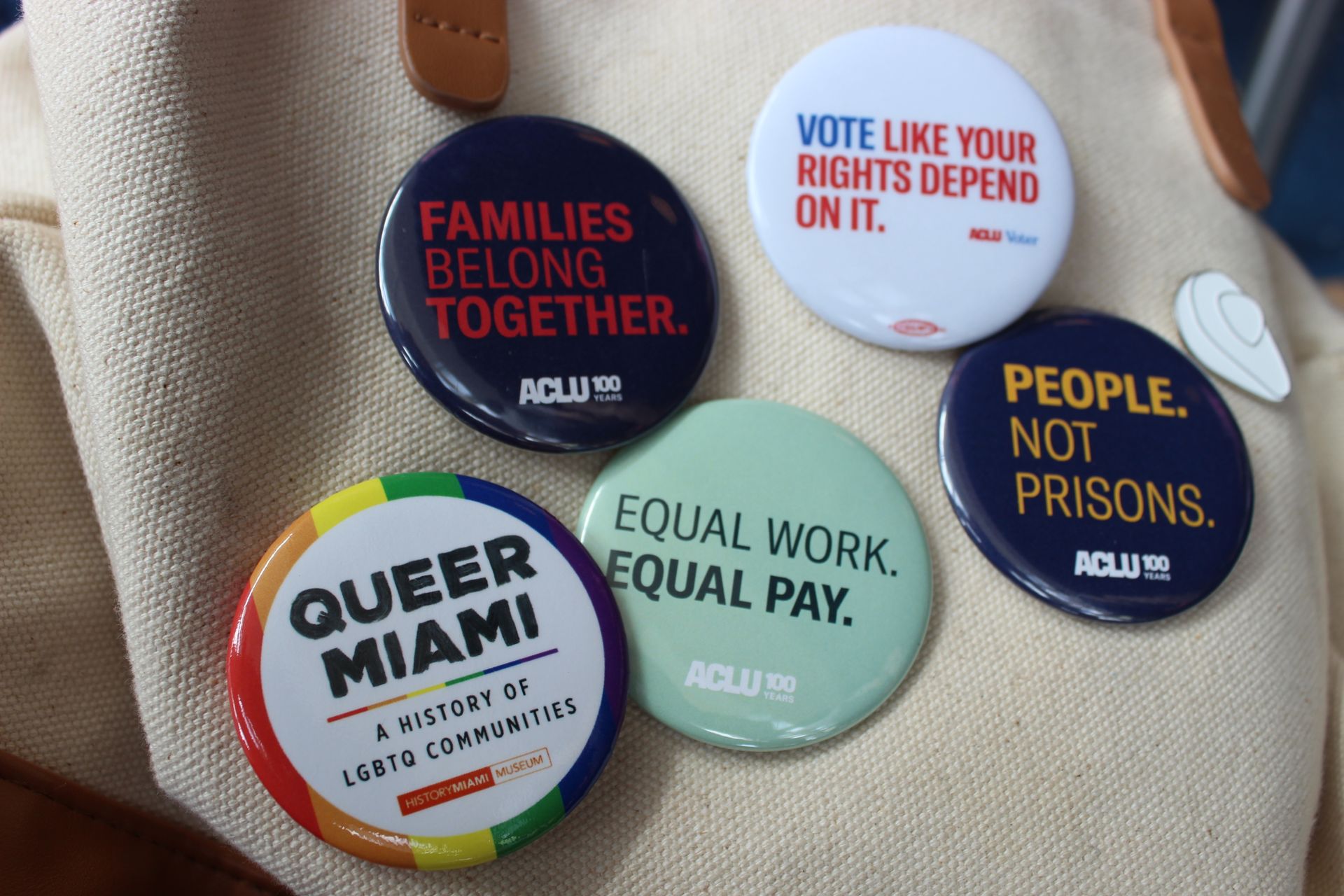 Vibrant political pins advocating equality and rights on a canvas bag.