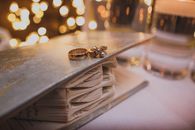 Golden wedding rings on decorated book in room for celebration with bright shiny lights