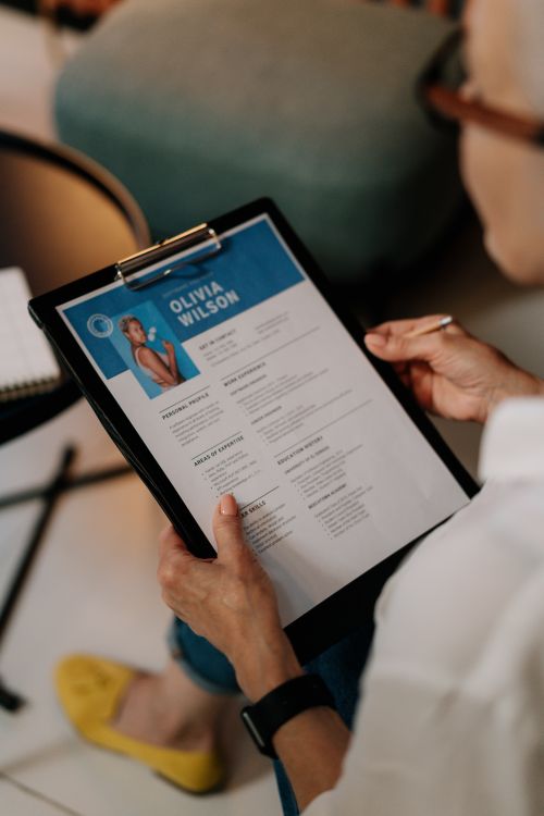 Free An HR professional reviews a resume on a clipboard during an office meeting. Stock Photo
