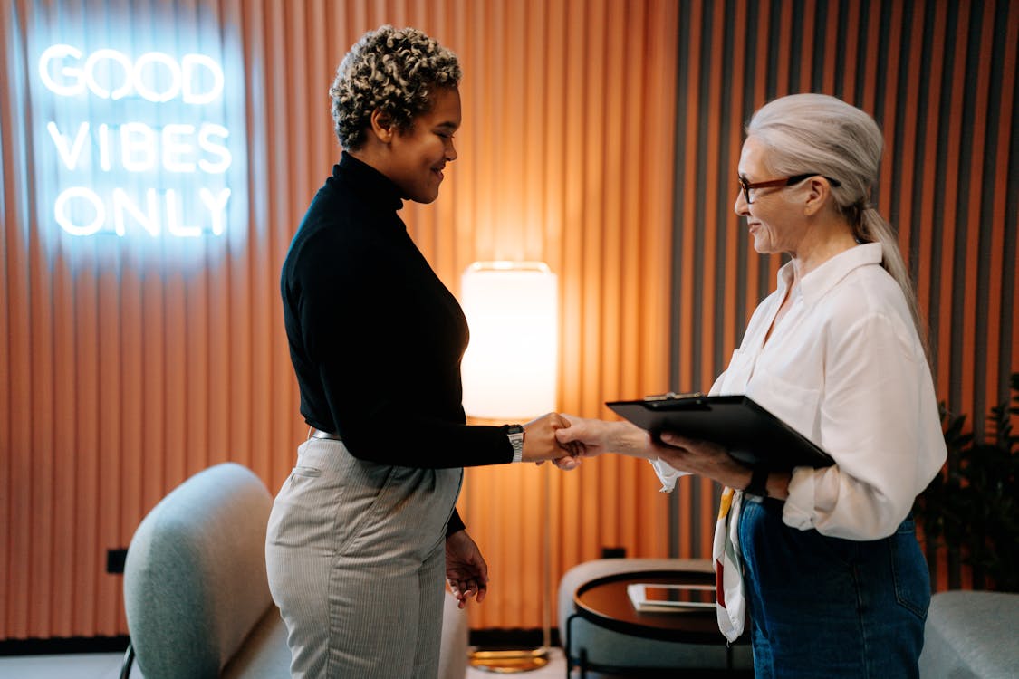 Image of two women shaking hands in an office environment. Recruit an apprentice