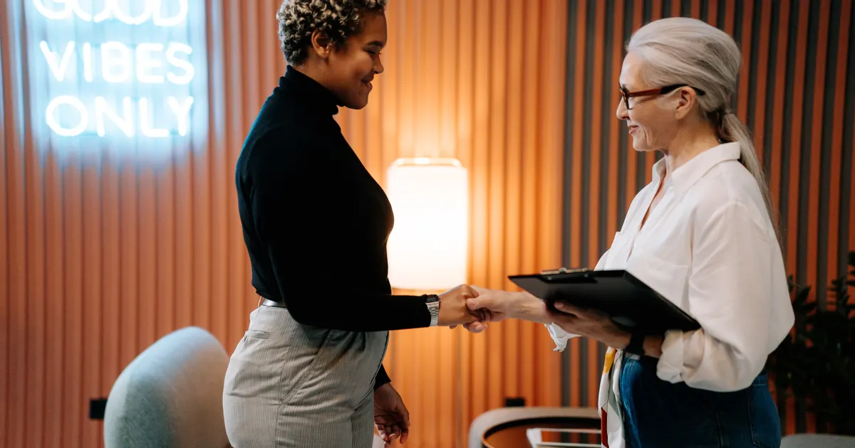 Two women shaking hands, one holding a clipboard, representing Connecticut SB 5 AI employer compliance October 2026