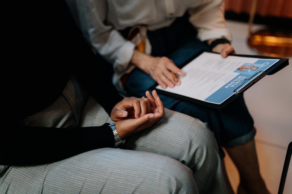 Free Person in White Long Sleeve Shirt Holding a Clipboard with Resume Stock Photo