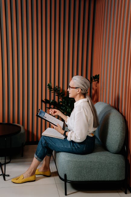 An adult woman in casual attire reviewing notes on a tablet in a stylish office setting.