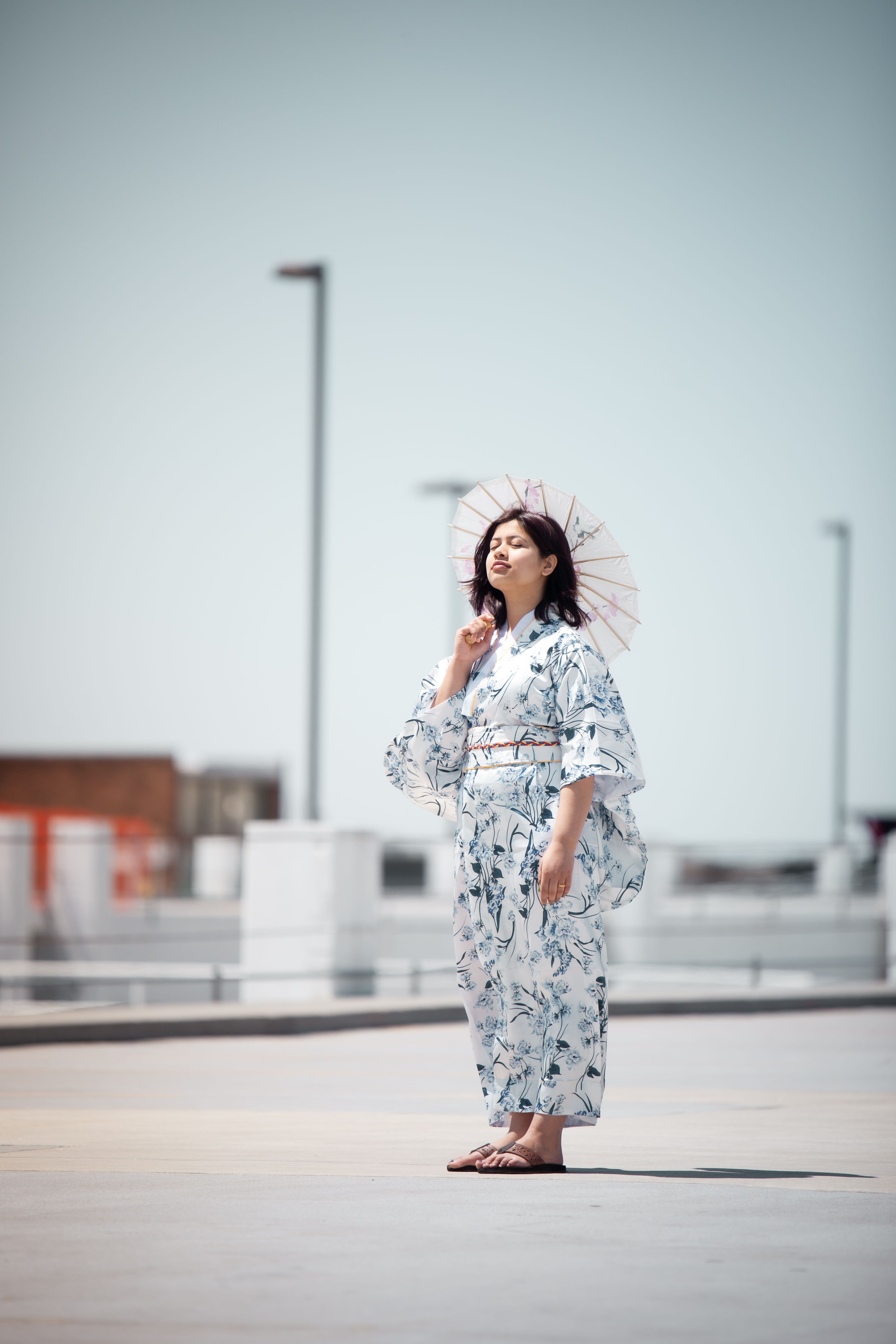 一名穿着和服的女子撑着遮阳伞，站在明亮的城区