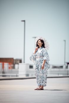一名穿着和服的女子撑着遮阳伞，站在明亮的城区