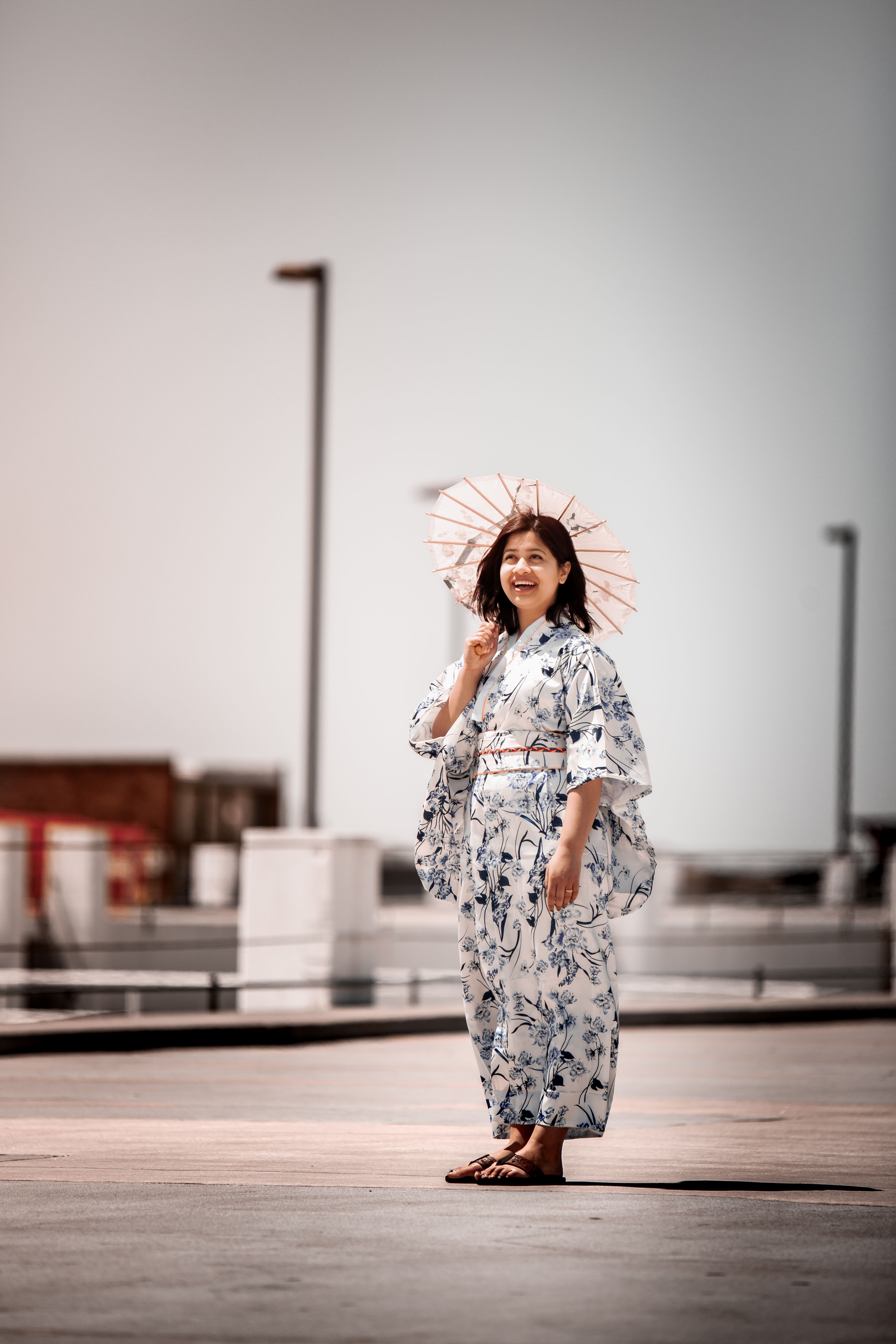 身着和服的女子撑着遮阳伞立于户外，体现了日本传统文化