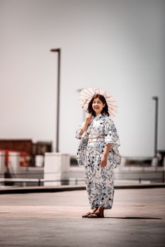 身着和服的女子撑着遮阳伞立于户外，体现了日本传统文化