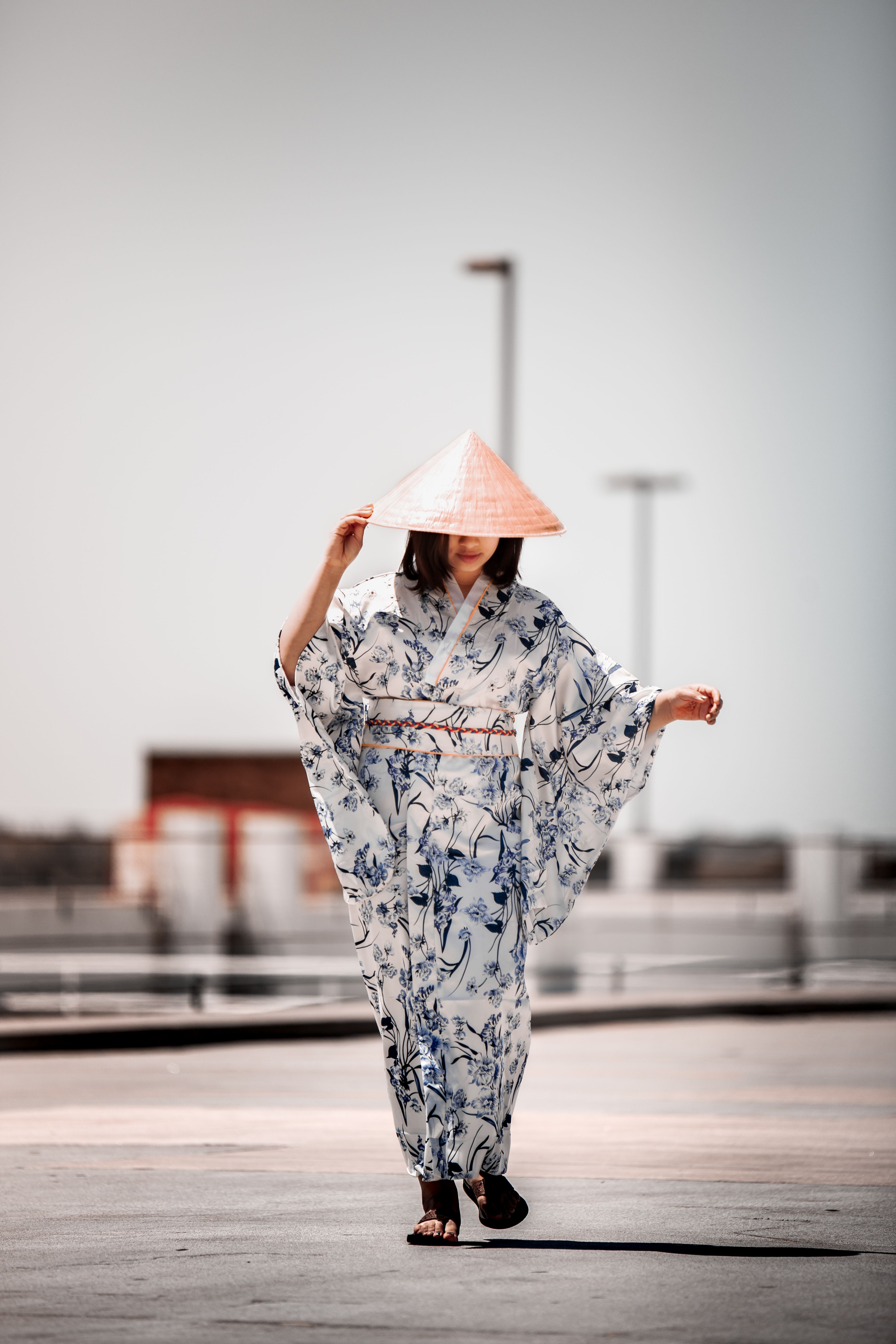 一名成年女子身着花卉和服，头戴圆锥帽，优雅地走在屋顶上