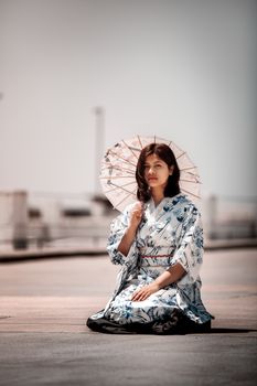 海边，一名身穿花卉和服的女子跪着撑伞