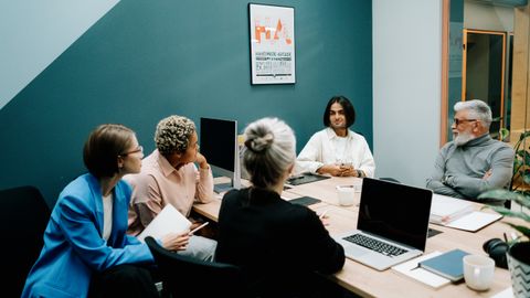 A diverse group of professionals engaged in a dynamic meeting in a modern office environment.