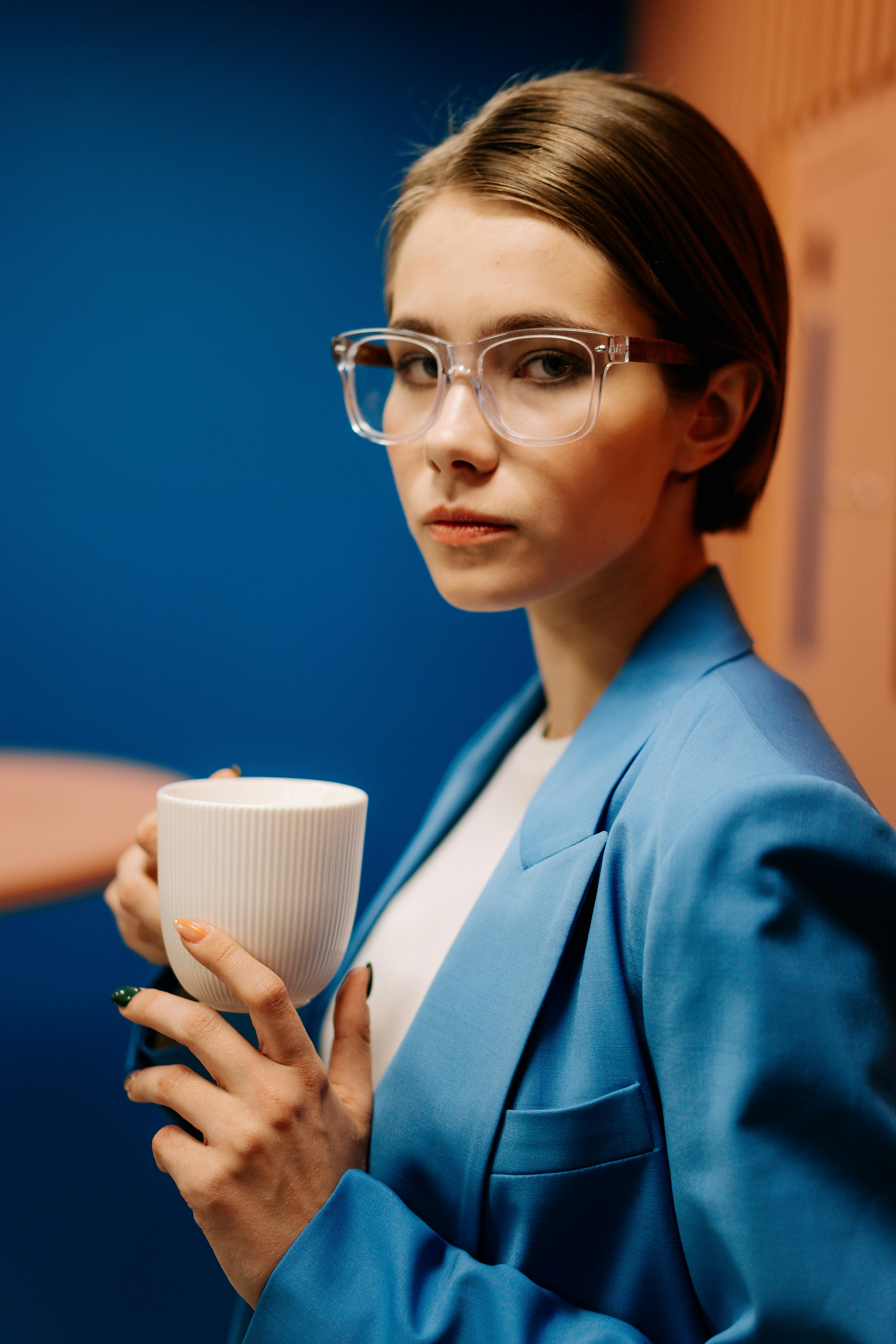 一位戴眼镜、拿着咖啡杯的年轻女子在现代办公环境中的肖像