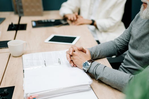 Close-up of a business meeting with documents and digital tablet on a wooden desk.