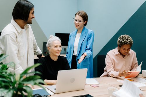Free A group of professionals engaged in a collaborative meeting at an office with laptops and documents. Stock Photo