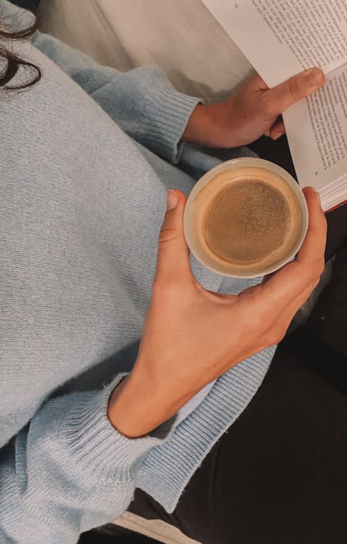 A Person Holding a Cup of Coffee and a Book