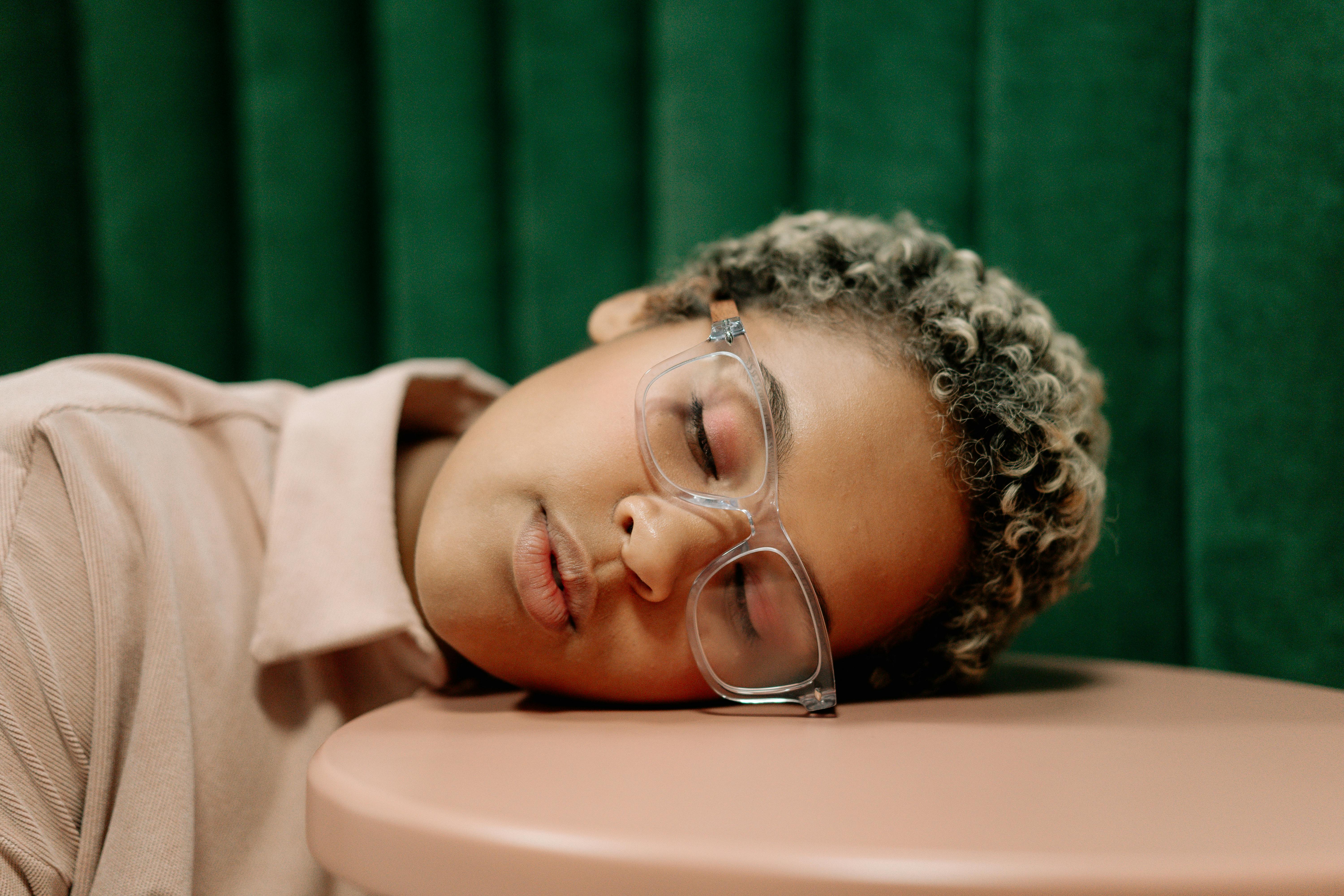 woman in white framed eyeglasses lying on bed