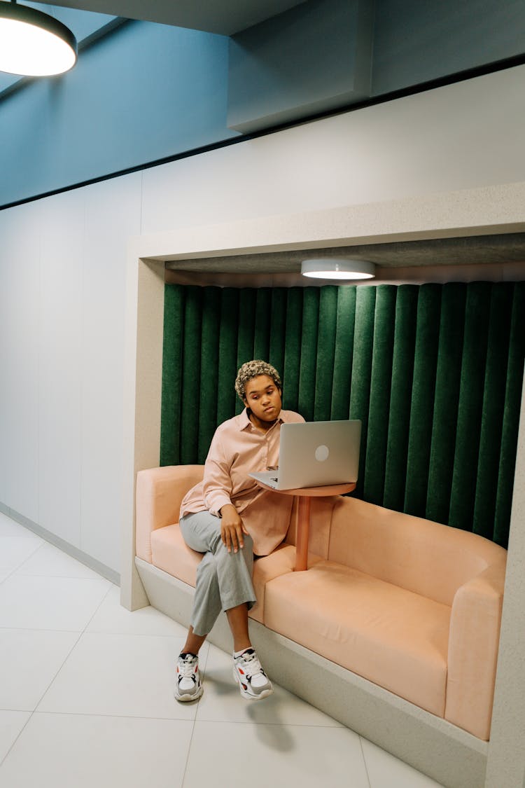 A Woman Sitting On A Couch While Using Her Laptop