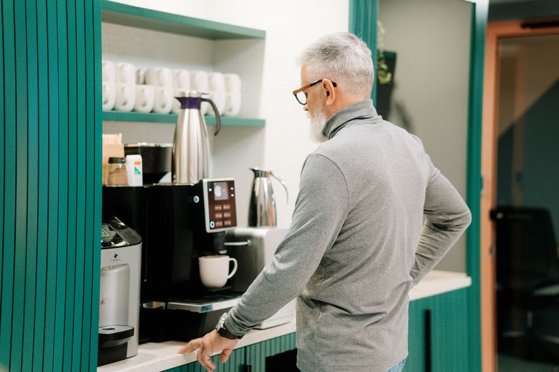 mason jar labeled coffee fund next to a coffee machine