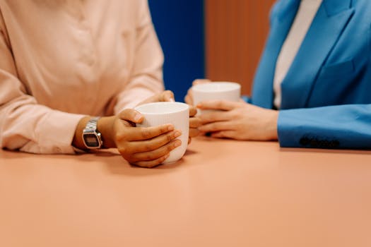 Two colleagues enjoying a coffee break, relaxing in a modern office setting.