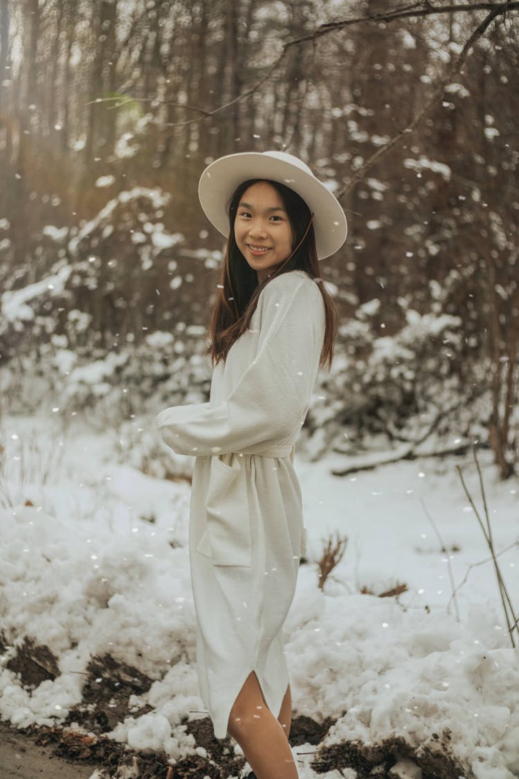 Happy Asian Woman In Dress Smiling In Winter Forest