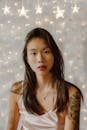 Delicate young Asian woman near wall with luminous garland