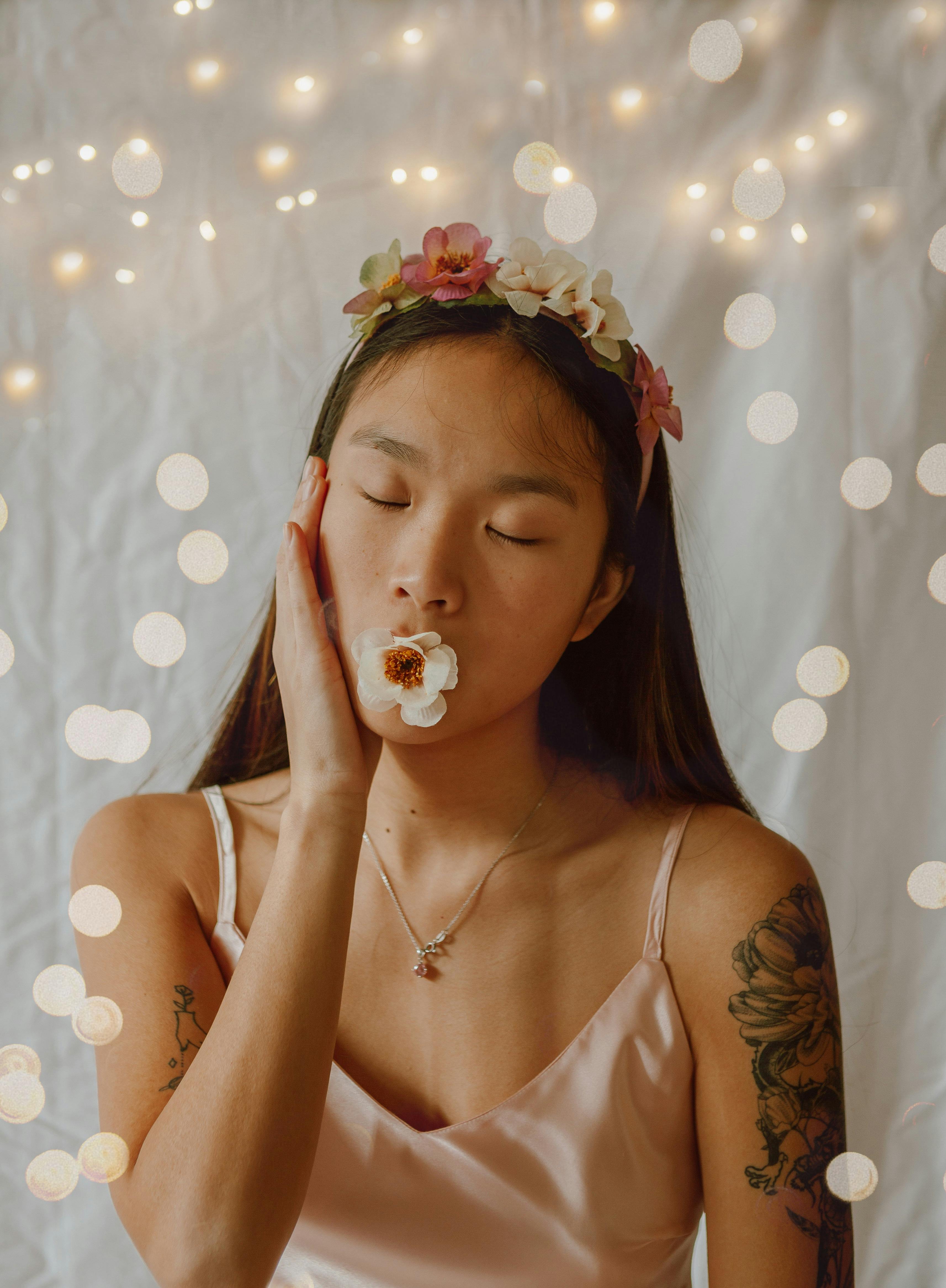 Artistic portrait of a young woman with a floral headdress and dreamy bokeh effect.